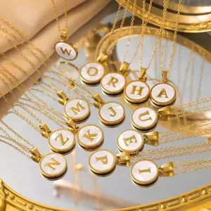 Gros plan détaillé de colliers avec pendentif initiale en nacre plaqué or 18 carats