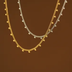 Detailaufnahme von 18K Gold- und Silberperlenketten auf mattbraunem Hintergrund