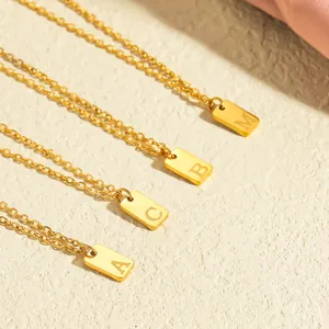 Macro detail of 18K gold plated rectangular pendants featuring engraved A B C M letters