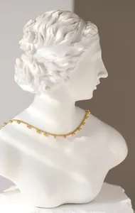 Minimalistische 18K vergoldete Perlenkette auf einer weißen künstlerischen Gipsstatue