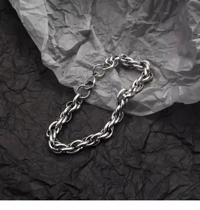 Détail macro du bracelet à maillons tressés argentés avec fermoir mousqueton sur fond gris