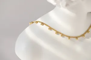 Detail der 18 Karat vergoldeten Kugelkette mit runden Metallperlen-Quasten an feiner Gliederkette