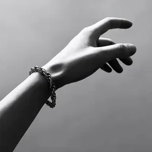 Gros plan d'un bracelet à gros maillons argentés au poignet avec éclairage artistique noir et blanc