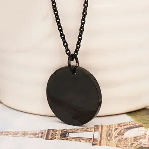 Detailed close-up of a minimalist black round titanium necklace pendant with link chain