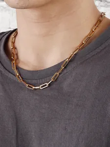 Primo piano di una collana a catena a graffetta dorata indossata da un modello uomo
