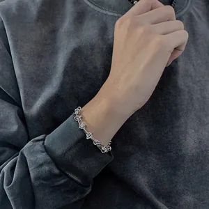 Gros plan d'un bracelet à maillons noués hip hop porté au poignet sur un sweat à capuche
