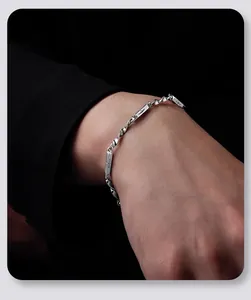 Vue détaillée du bracelet gourmette Mobius argenté porté au poignet sur tissu noir