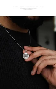 Close-up of a silver compass pendant necklace with detailed engraved geometric patterns