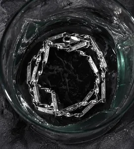 Gros plan d'un bracelet en acier titane avec croix immergé dans l'eau montrant l'étanchéité