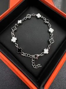 Detail of silver chain bracelet with black and white enamel cross charms in a gift box