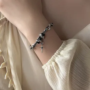 Gros plan du bracelet punk double couche avec plaque noire et pendentif croix argentée