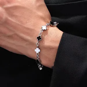 Detail of silver titanium steel bracelet with black and white cross pendants on a wrist