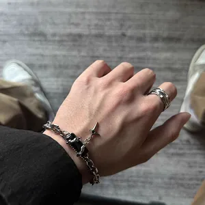Détail de bracelet chaîne argentée avec pierre noire et pendentif étoile au look urbain