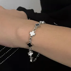 Close-up of titanium steel cross bracelet with black and white enamel link details