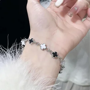 Close-up of titanium steel cross bracelet with black and white charms on a wrist