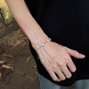 Detail of silver titanium cross bracelet worn on wrist with black shirt outdoors