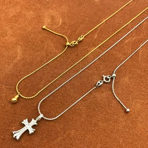 Macro detail of adjustable sliding clasp on gold gourd and silver cross necklaces
