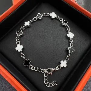 French luxury cross bracelet with black and white enamel charms in an orange gift box