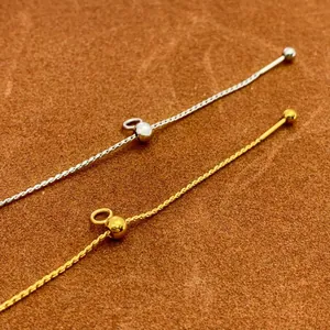 Detailed view of 18K gold and silver adjustable needle chains on brown suede background