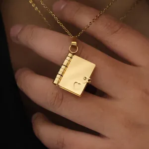 Detailed view of an opening heart-shaped gold book pendant necklace on a delicate chain