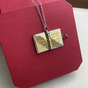 Close-up of heart-shaped book locket necklace with engraved text on red gift box