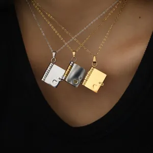 Three stacked heart book locket pendants in gold, silver and black steel on a model