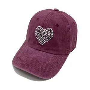 Detailed close-up of wine red washed cotton baseball cap with rhinestone heart design