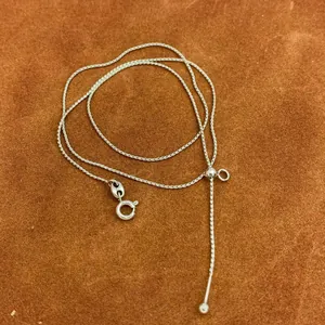 Detail view of silver needle-end chain with adjustable slider bead and spring clasp