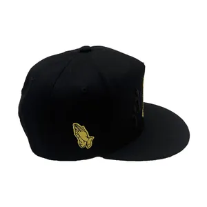 Cappellino snapback nero con ricamo a croce e mani in preghiera gialle sul lato