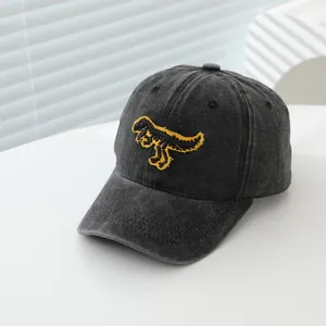 Détail de la broderie squelette de dinosaure jaune sur une casquette en coton gris foncé