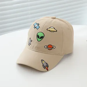 Detailed close-up of cartoon alien and UFO embroidery on a khaki cotton kids baseball cap
