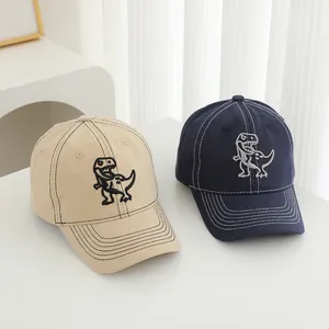 Detail of beige and navy baseball caps featuring dinosaur embroidery and contrast stitching