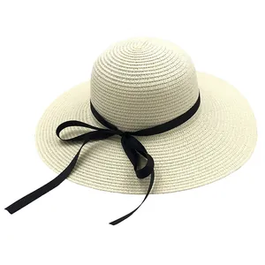 Détail de la texture tressée et du nœud noir élégant sur le chapeau en paille crème