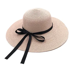 Détail de chapeau en paille beige à large bord avec un élégant nœud en ruban noir