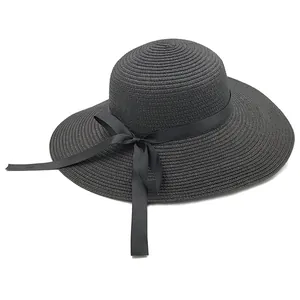 Gros plan détaillé d'un chapeau de paille noir à larges bords avec nœud en ruban de satin