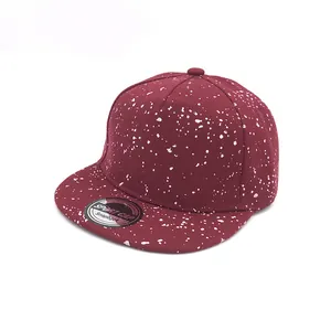 Close-up of burgundy snapback hat featuring white splash ink patterns and a sport cap label