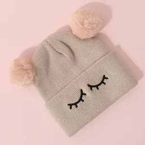 Dettaglio cappello bimbo in maglia con pompon rosa e ricamo a ciglia sul bordo risvoltato