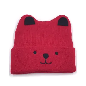 Detailed close-up of a red knitted baby hat with cute black cat ears and embroidered face