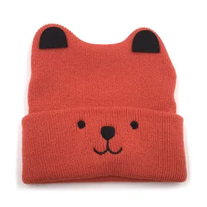 Winter knitted baby hat in warm brick red with cute black bear ears and embroidery