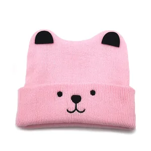 Close-up of pink knit baby beanie with black 3D ears and cute cartoon animal face