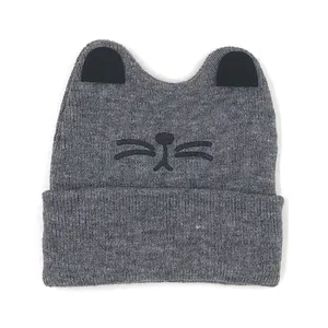 Grey knit baby winter hat with cute cat ears and embroidered whiskers on white background
