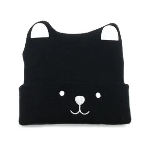 Close-up of black knit baby beanie featuring white bear ears and detailed facial embroidery