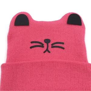 Detail of pink knitted baby beanie with cat ears and embroidered whiskers pattern