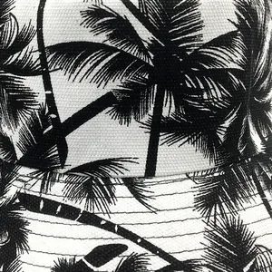 Retro canvas bucket hat featuring black coconut tree palm prints on white fabric