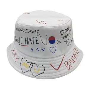 Detailed view of white canvas bucket hat with street style graffiti prints and slogans