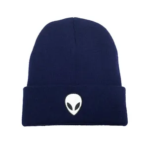 Gros plan sur la broderie alien blanche d'un bonnet en maille bleu marine pour l'hiver