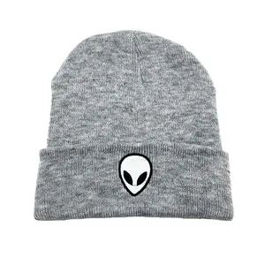 Détail d'un bonnet gris en maille avec broderie alien blanche sur le bord plié