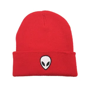 Gros plan sur le bonnet en tricot rouge avec broderie d'alien détaillée sur le bord replié