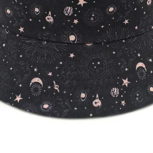 Reversible bucket hat with black universe print featuring stars, moons, and planets