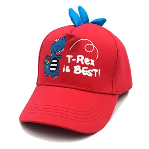 Détail d'une casquette enfant rouge avec cornes 3D et motif de dinosaure de dessin animé